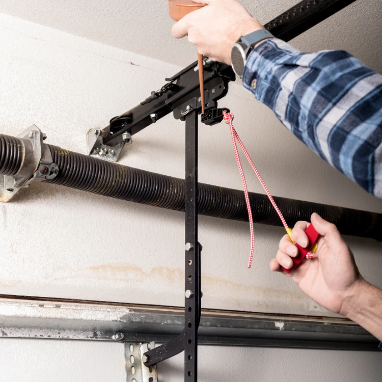 Technician demonstrating the manual operation of a garage door opener with the emergency pull cord